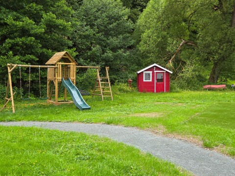 Für die Kinder gibt es im gro&szlig;en grünen Garten eine Rutsche und Schaukeln   Ferienhaus Haus am Bach   Referinghausen im Sauerland